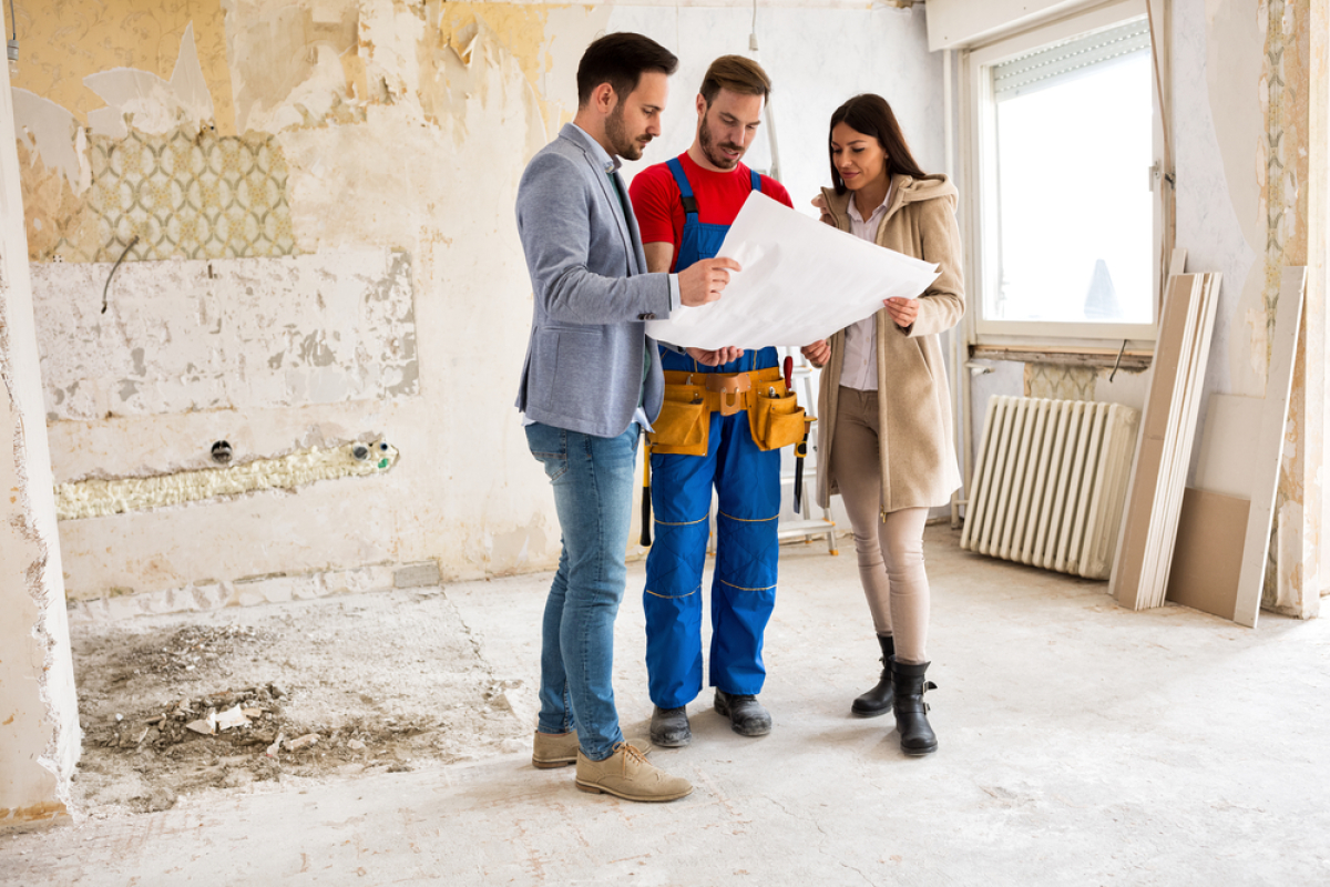 garantie constructeur immobilier – couple vérifie les plans avec un ouvrier